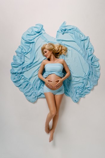 tehotna mamicka leziaca na zemi v dlhych modrych satach